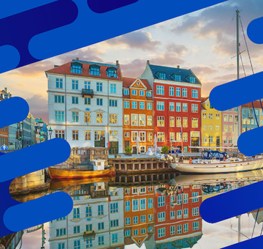 Colorful buildings and sailboats reflected in the water at Nyhavn Harbor in Copenhagen, Denmark.