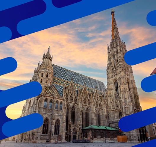 Cathedral with a patterned tiled roof and tall spire at sunset, framed by blue graphic elements