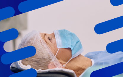 Patient wearing a surgical cap and mask lying beneath a Centurion Vision System monitor during an ophthalmic procedure.